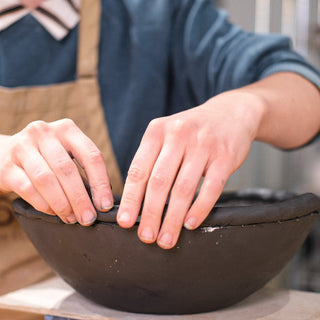 Person working on a pottery piece with a blurred background